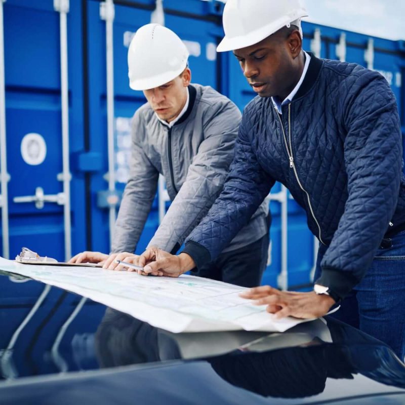 two-engineers-discussing-building-plans-together-in-a-freight-yard.jpg